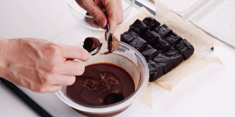 Scooping chocolate ganache into spheres for making mochi.