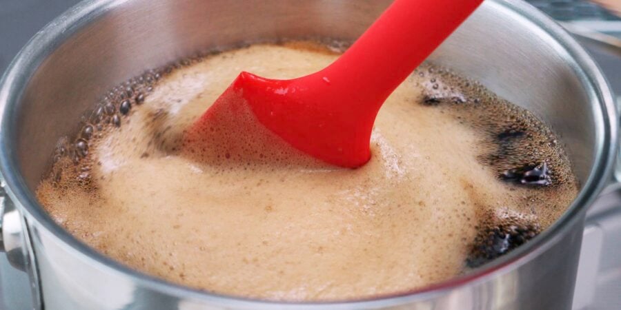Stirring coffee jelly in a pot with a red spatula.