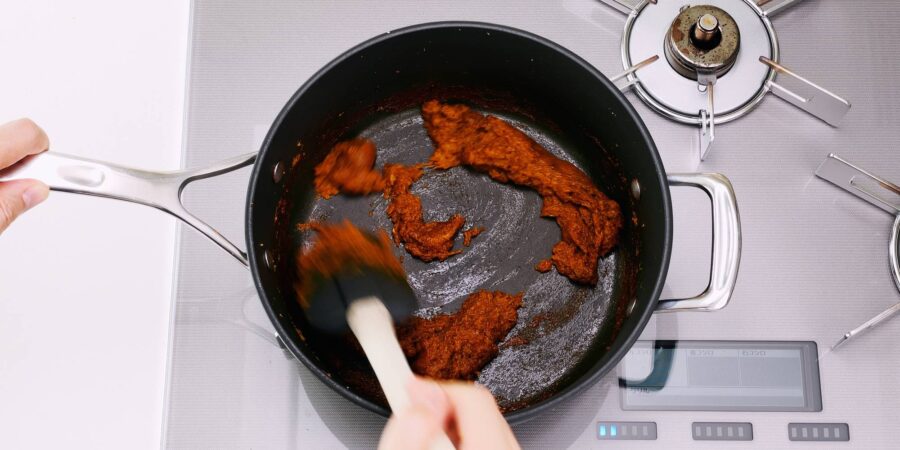 Caramelized grated aromatics with curry powder in a pot.