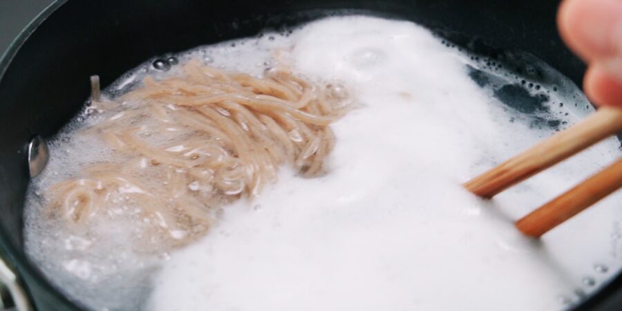 A pot of boiling water with soba noodles.