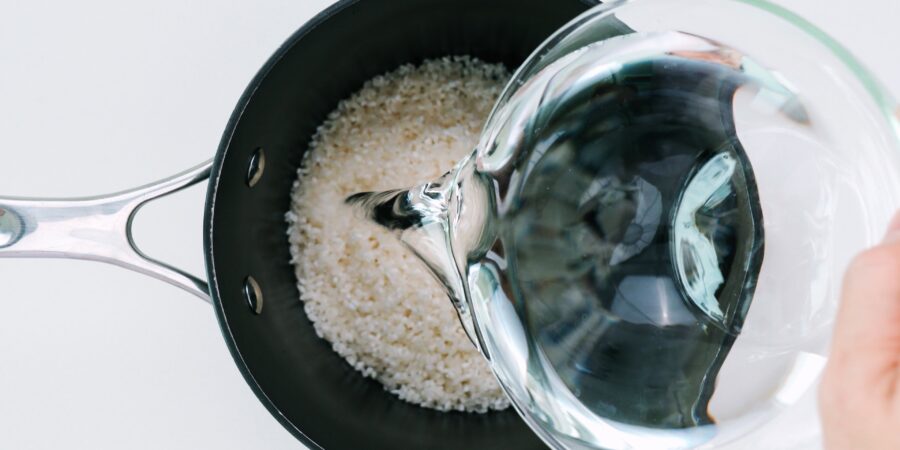 Adding water to a pot of sushi rice.
