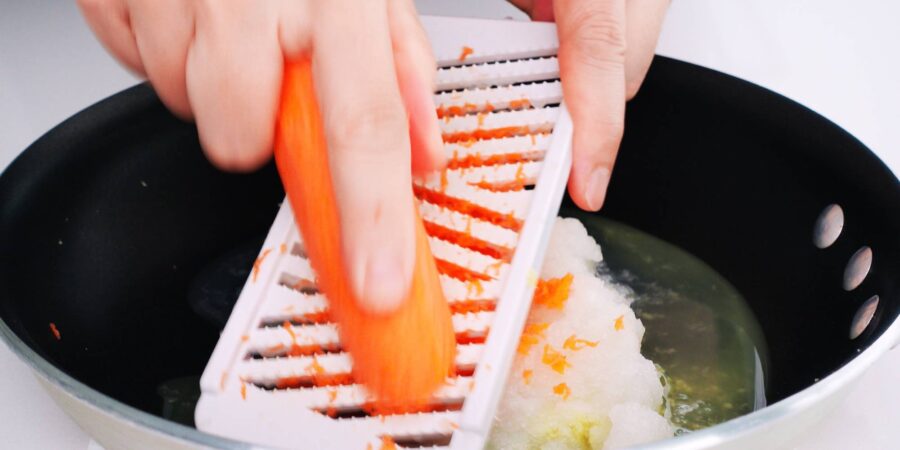 Grating carrots and onions into a pan for making Japanese curry sauce.
