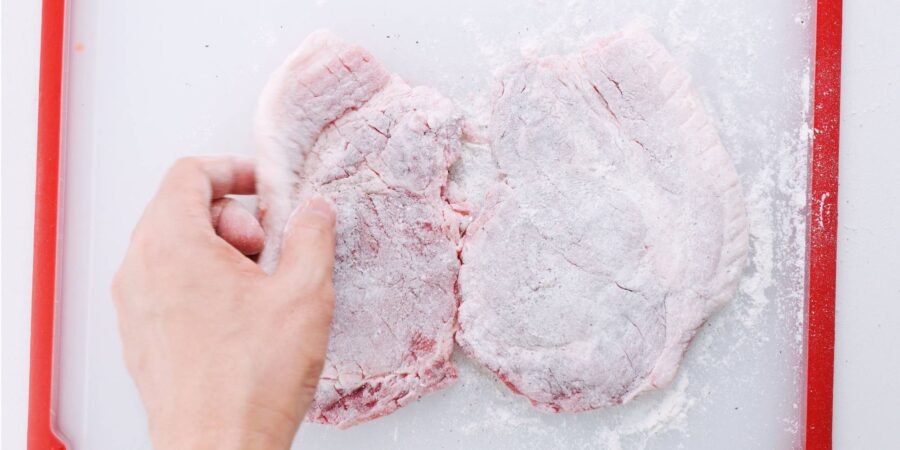 Pork cutlets dusted with flour for making katsu.