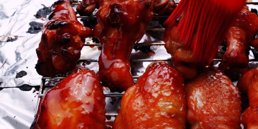 Glazing chicken wings with glossy teriyaki sauce.