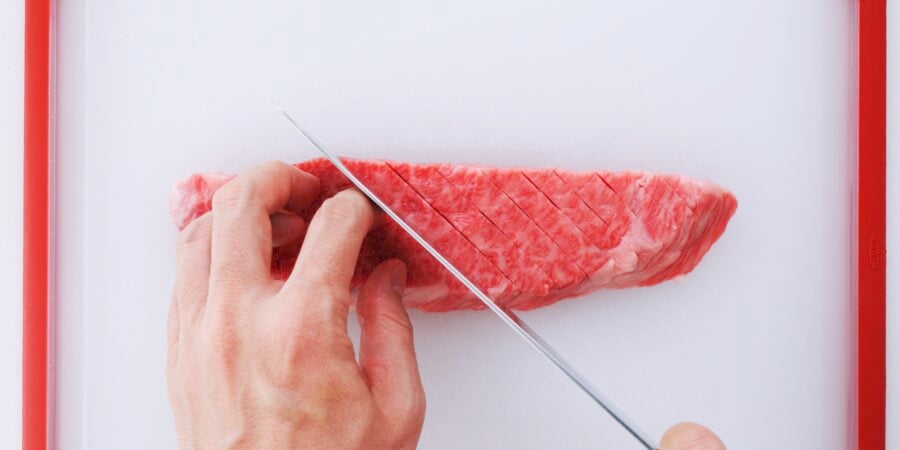 Tenderize the steak by cutting slits in it.