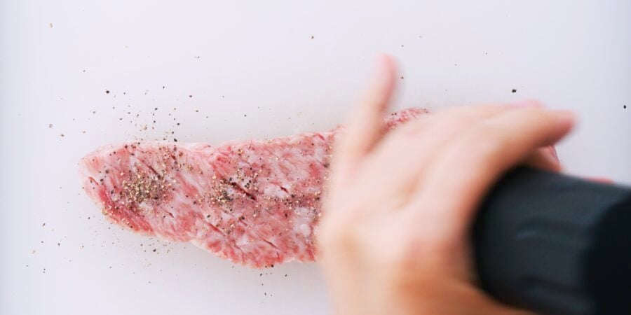 Season the tenderized steak with black pepper.