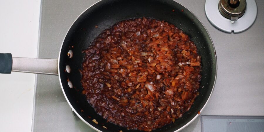 Pan of sauteed onions being deglazed with red wine.