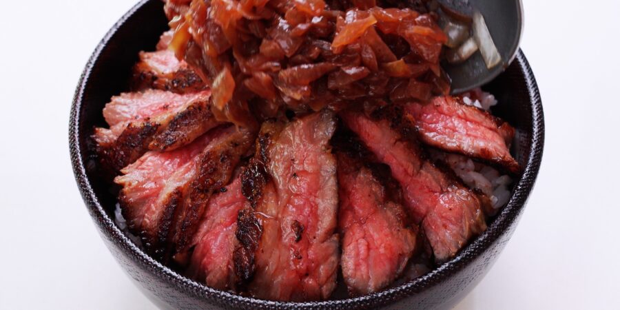 Rice bowl topped with sliced Chaliapin Steak and onion sauce.