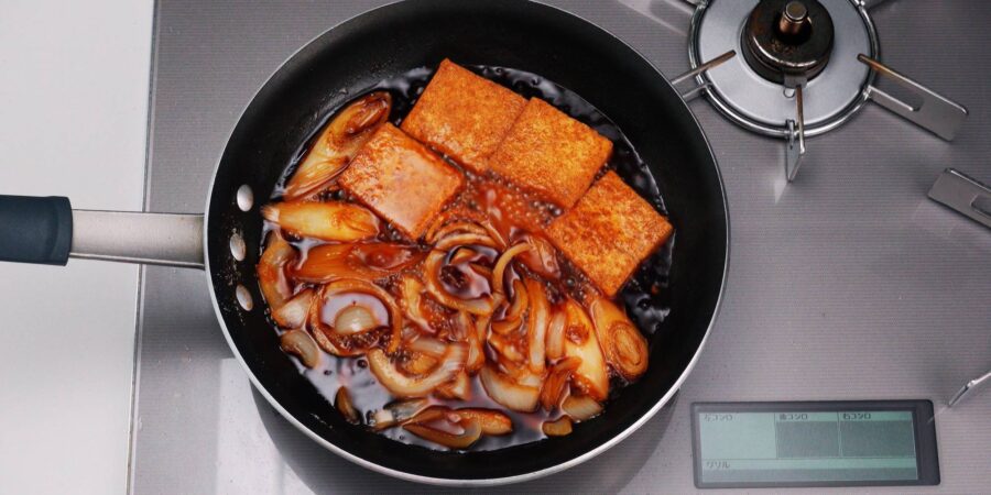 Simmering onions, scallions and tofu in a savory sweet sauce for gyunabe.