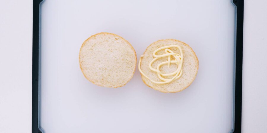 Spread mayonnaise on the bottom bun.