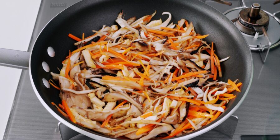 Sauteing a mixture of root vegetables and mushrooms for cooking with Takikomi Gohan.