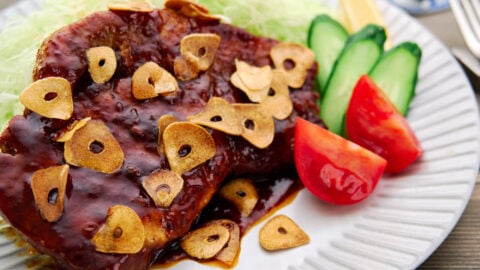 This tender, juicy Japanese pork steak, or Tonteki, is glazed in a savory sweet sauce and topped with crispy fried garlic.
