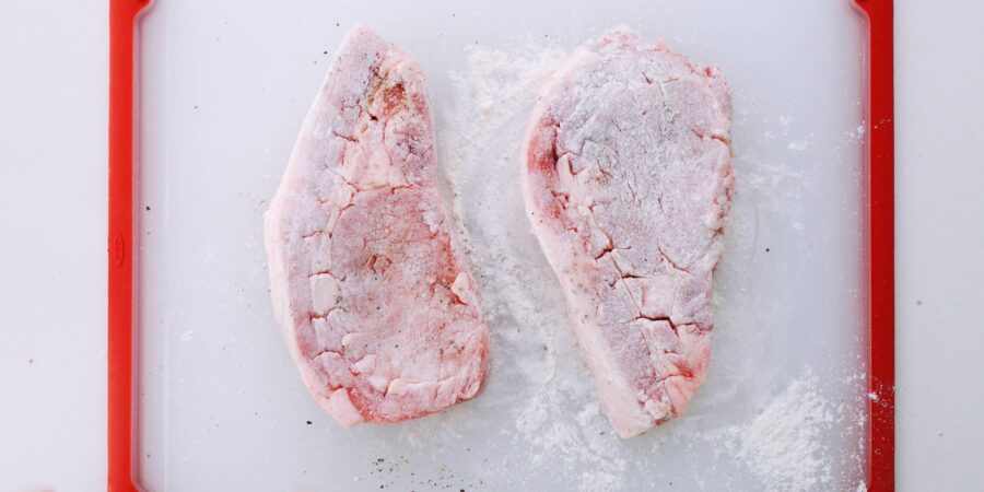 Pork steaks seasoned with salt and pepper and dusted with flour.