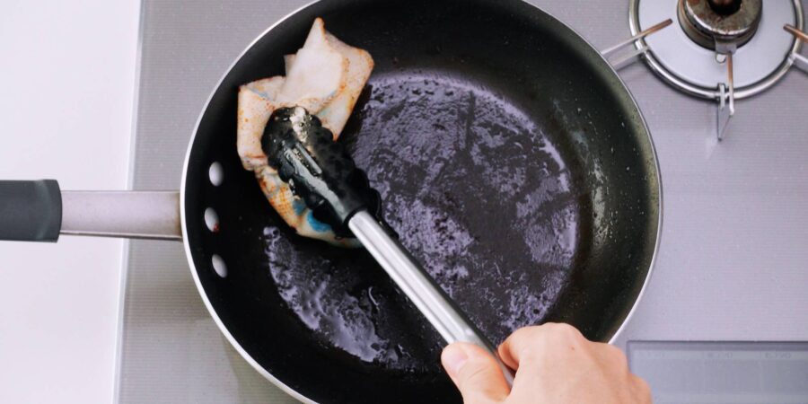 Wiping out the excess oil from the pan.