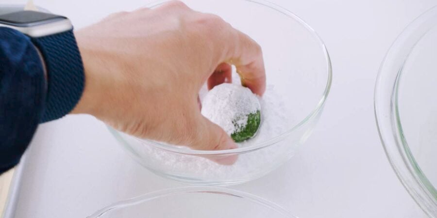 Rolling matcha cookie dough in powdered sugar.