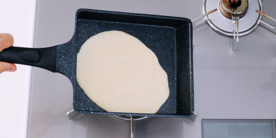 Spreading vegan tamagoyaki mixture in pan.