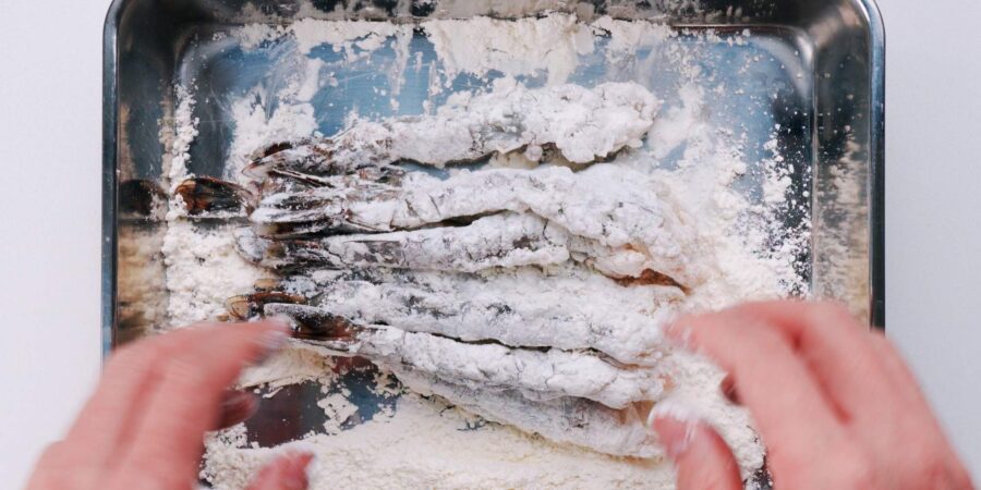Dusting shrimp with flour for making tempura.