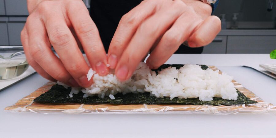 Spreading out vinegared sushi rice on nori.