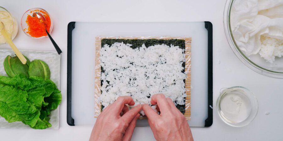 Spreading sushi rice on a sheet of nori.