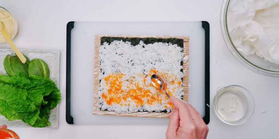 Spreading tobiko on sushi rice and nori.