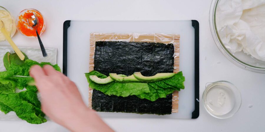 Lettuce and avocado on nori to make a sushi roll.