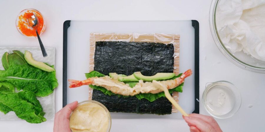 Shrimp tempura, karashi mayo, avocado and lettuce in a sushi roll.