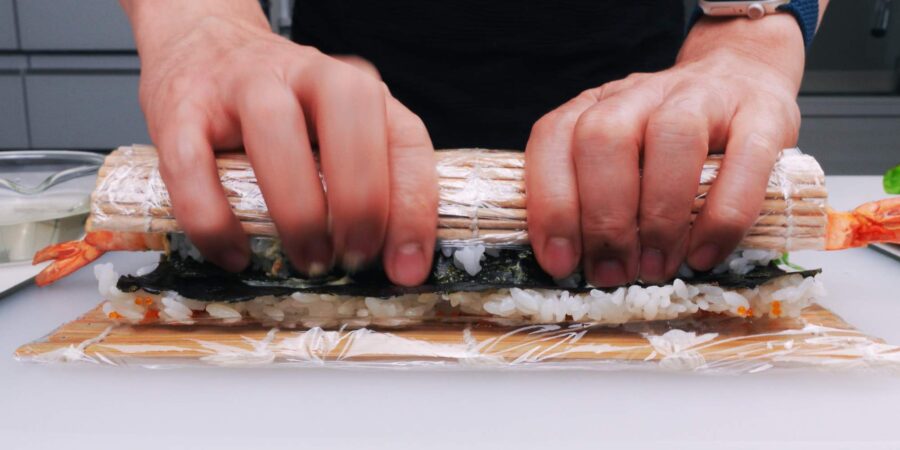Rolling sushi roll with a bamboo sushi mat.