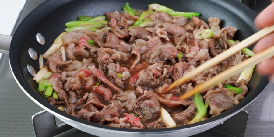 Thinly sliced beef for niku udon cooking in broth.