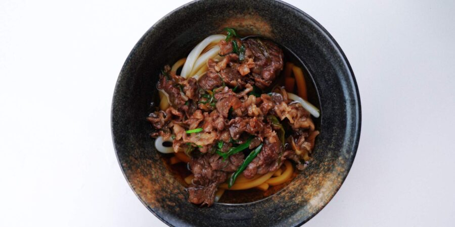 Beef udon noodle soup in a serving bowl.