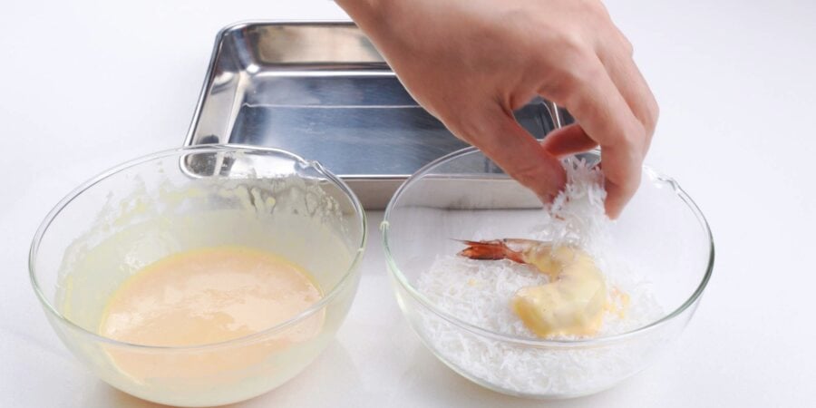 Battering and then covering the shrimp with shredded coconut.
