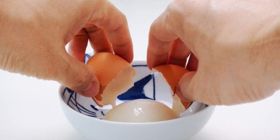 Cracking hot spring egg into a small bowl.