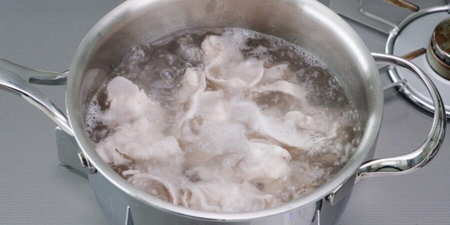Pork belly slices in boiling water.
