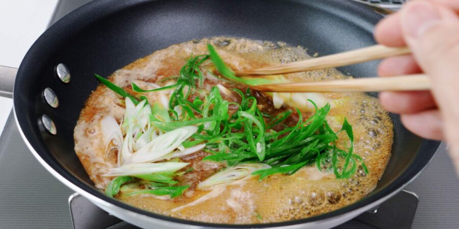 Simmering garlic sauce with sliced scallions.
