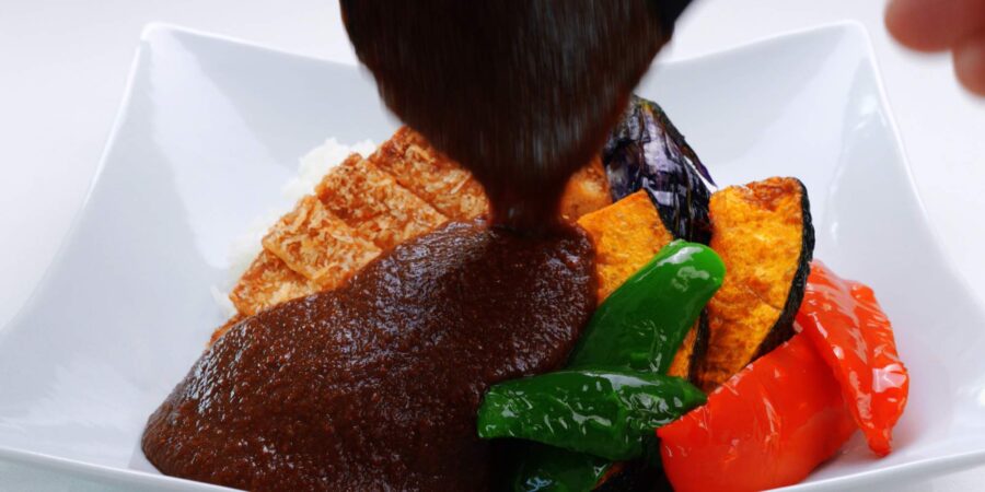 Pouring curry sauce over katsu and rice.