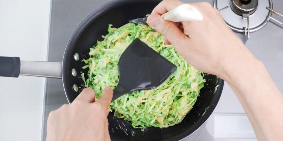 Shaping okonomiyaki in a frying pan.