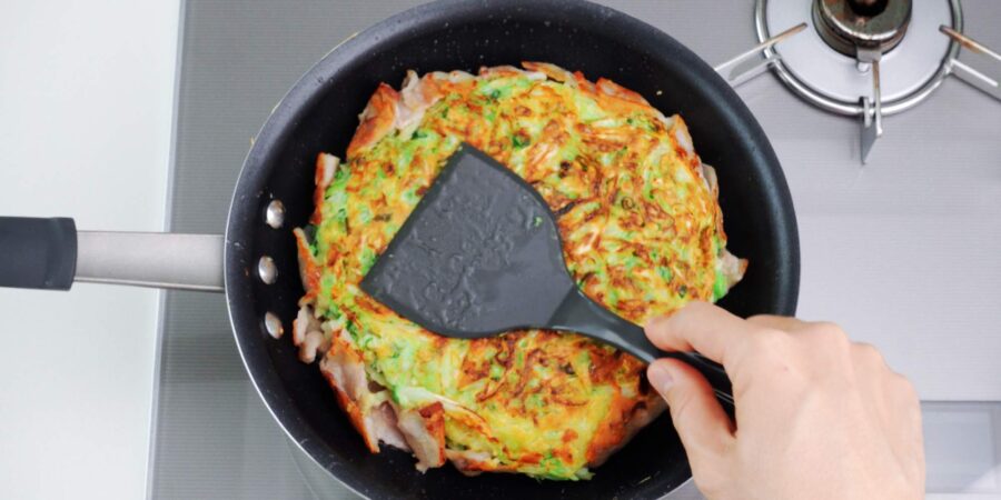 Shaping Okonomiyaki with a spatula.