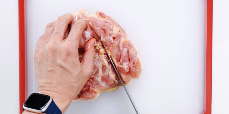 Cutting chicken thigh into strips.