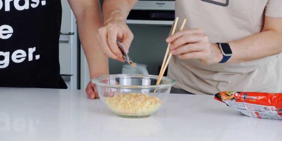 Mixing seasoning packet into cooked ramen noodles.