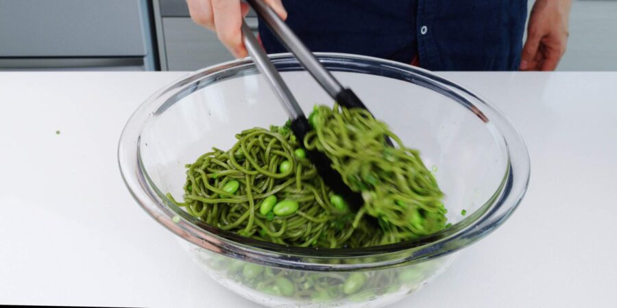 Tossing soba salad with edamame, scallions and sesame dressing.