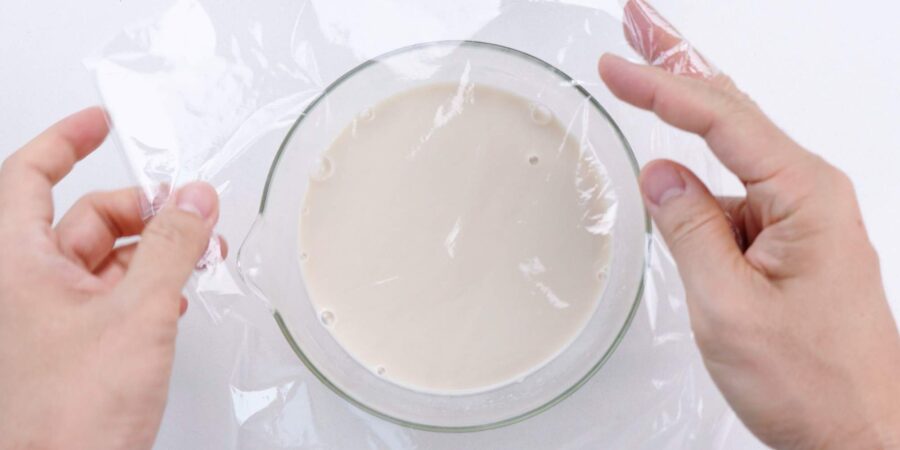 Covering sesame soup with plastic to refrigerate and chill.