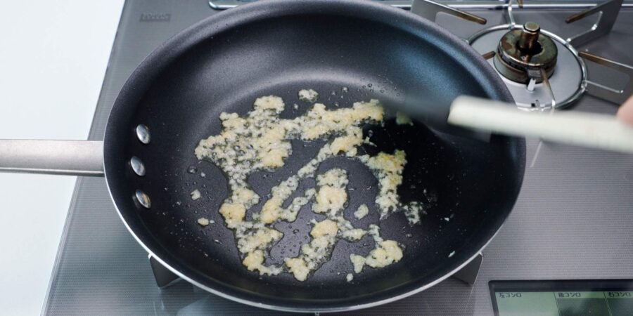 Frying garlic and ginger in a frying pan.