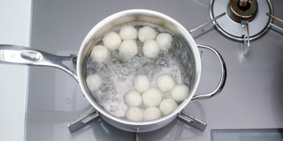 Dango floating in a pot of boiling water.