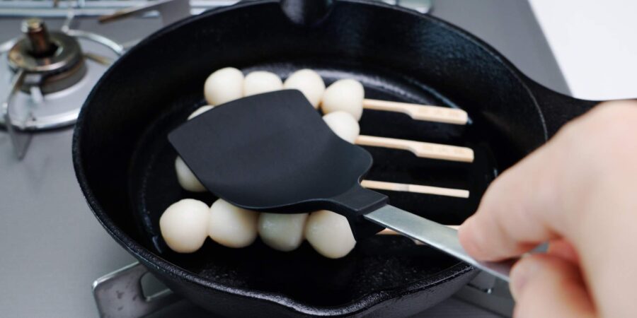 Grilling Mitarashi Dango on a cast iron skillet.