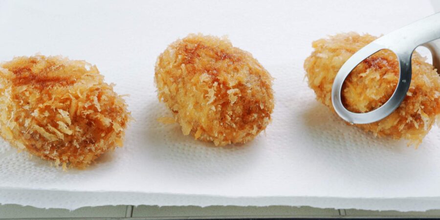 Draining fried potato croquettes on paper towels.