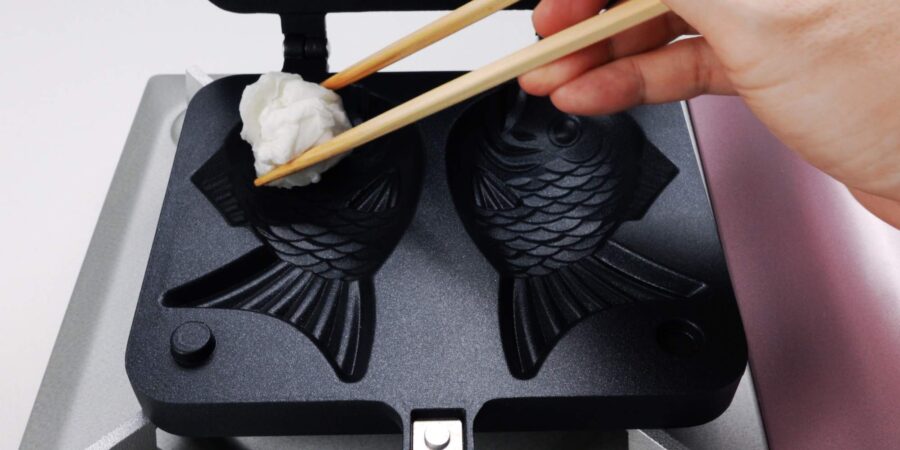 Greasing a Taiyaki mold with an oiled paper towel.