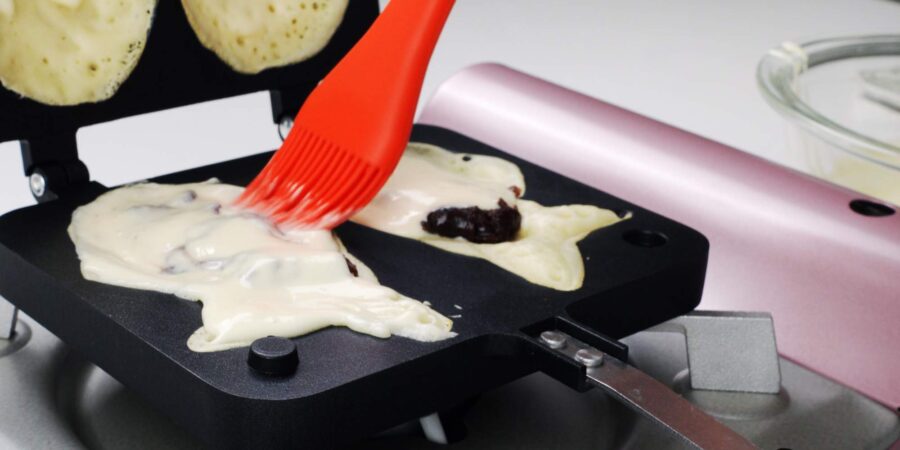 Adding another layer of Taiyaki batter to the pan.