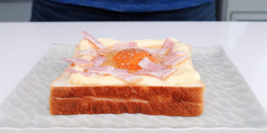 Topping egg toast with chopped bacon.