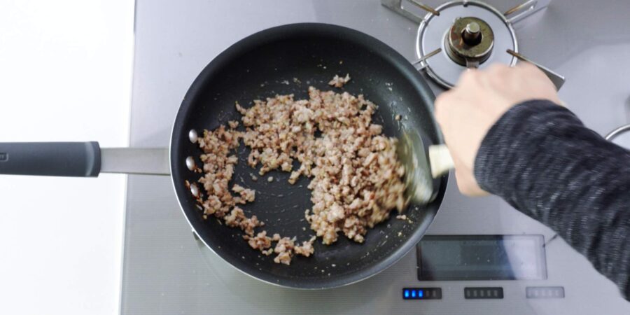 Stir-frying ground pork for mapo eggplant.