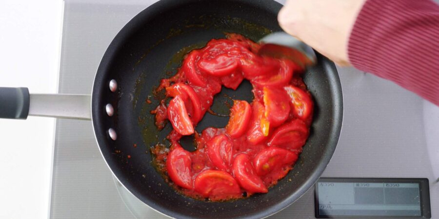 Stir-frying tomatoes in a frying pan.