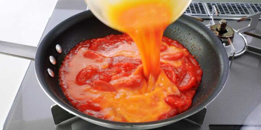 Adding eggs to stir-fried tomatoes.